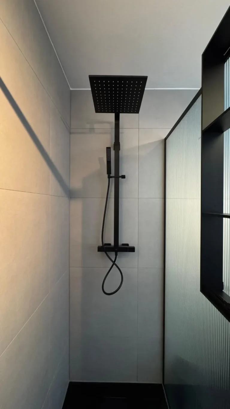 Moderne badkamer met zwarte regendouche en lichte wandtegels