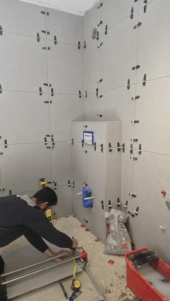 Vakman plaatst grote wandtegels in badkamer tijdens renovatie in Gorinchem