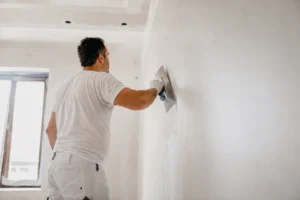 Stukadoor werkt aan een strakke muur in een lichte woning.